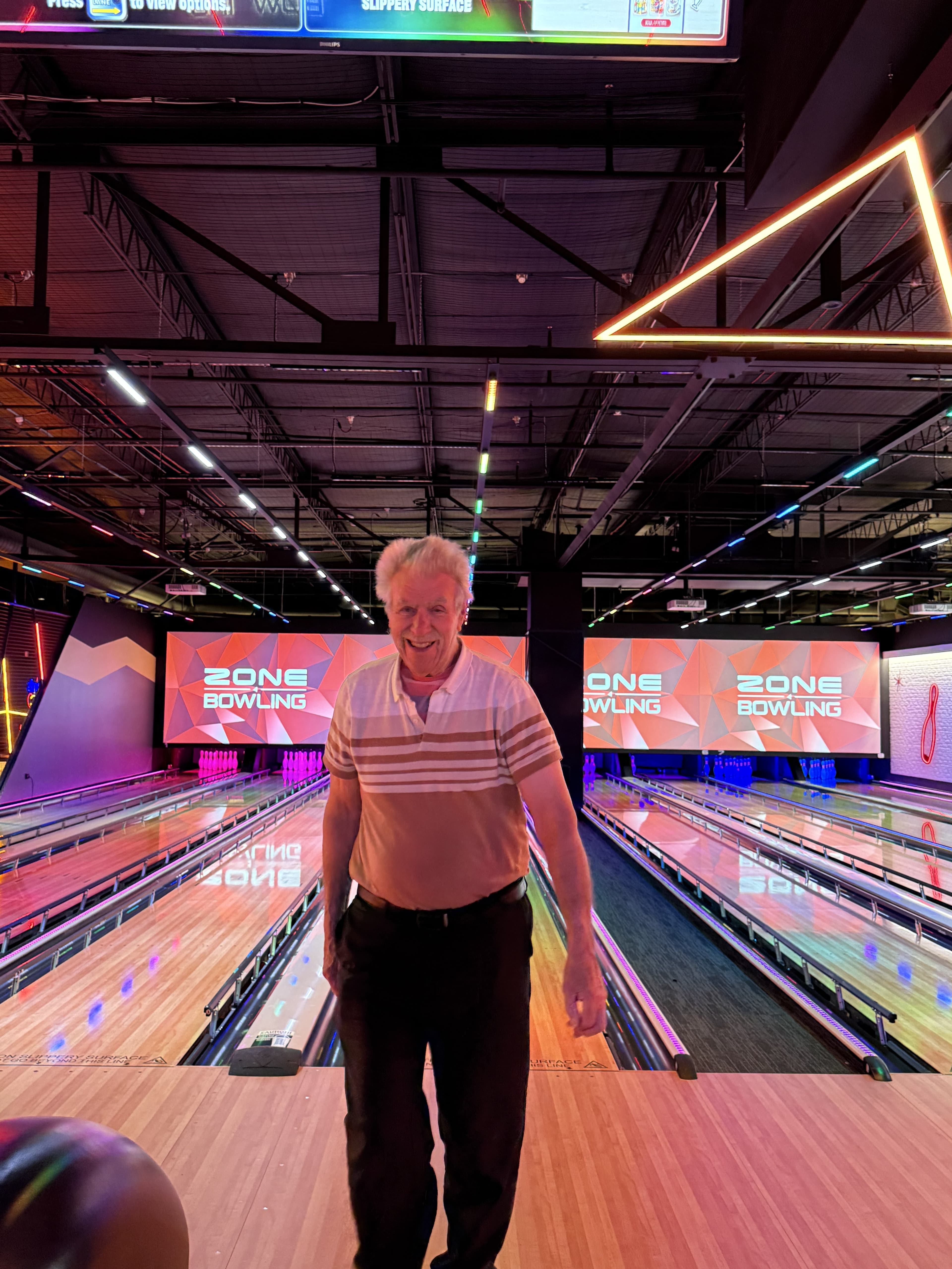 A participant at the bowling alley, lanes lit up behind.
